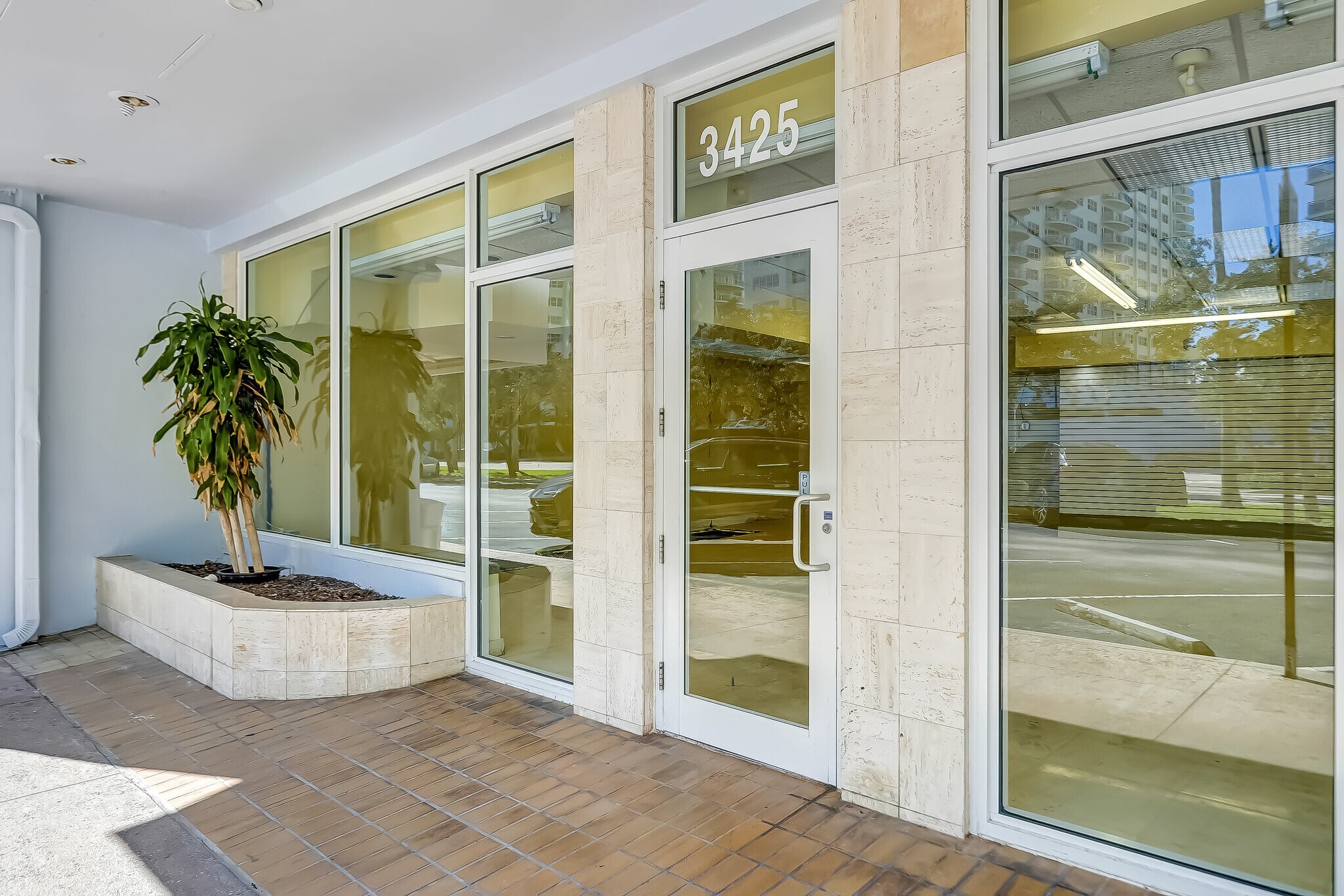 Front entrance of 3425 Galt Ocean Drive with travertine stone surround, glass door, and the suite address above